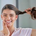 ragazza sorridente tiene la ciocca di capelli sani e forti