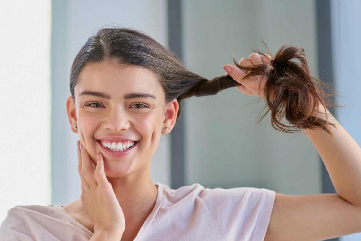 ragazza sorridente tiene la ciocca di capelli sani e forti