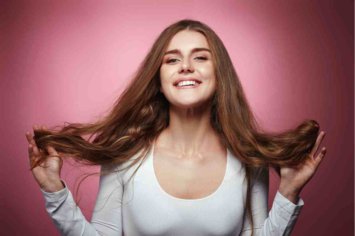 ragazza sorridente con le mani tra i capelli