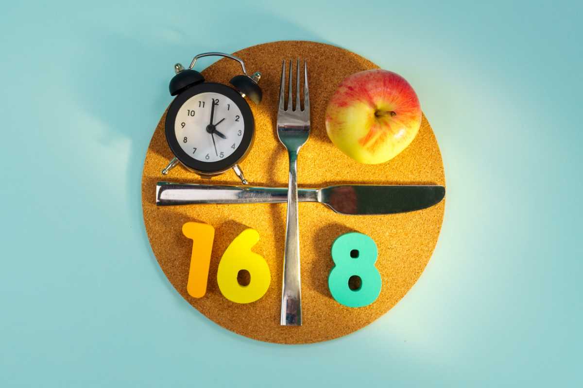 un piatto con posate, mela, sveglia e numeri 16 e 8