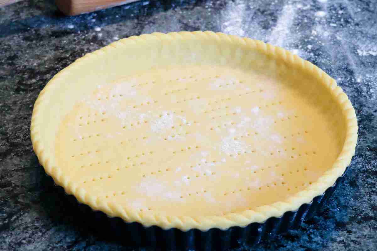 Pasta frolla senza glutine stesa in una teglia per fare la crostata