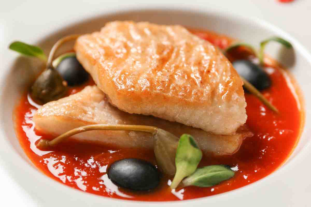 due filetti di pesce con sugo e pomodoro in un piatto